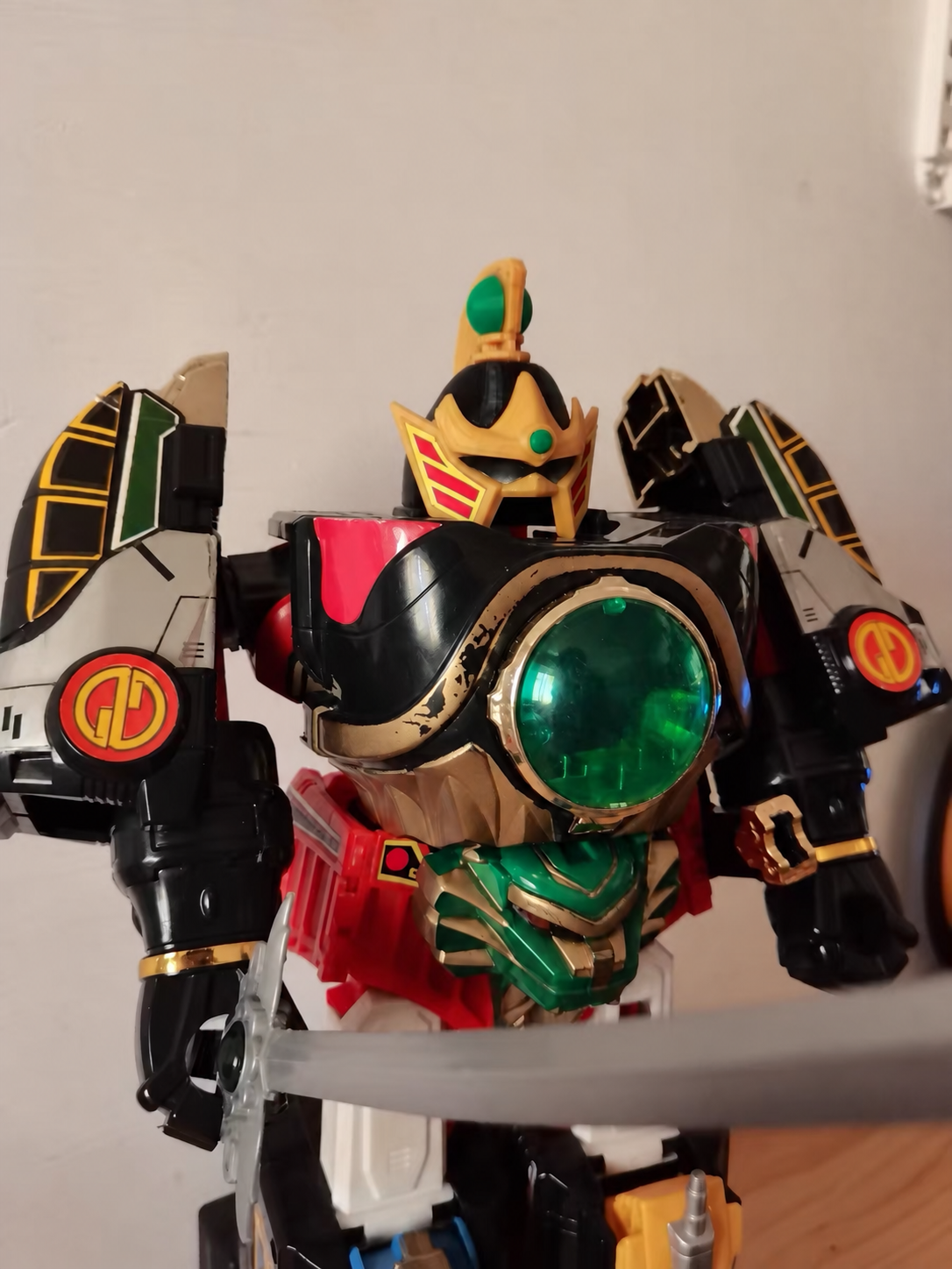 Vintage black and gold mecha robot with green chest orb and sword